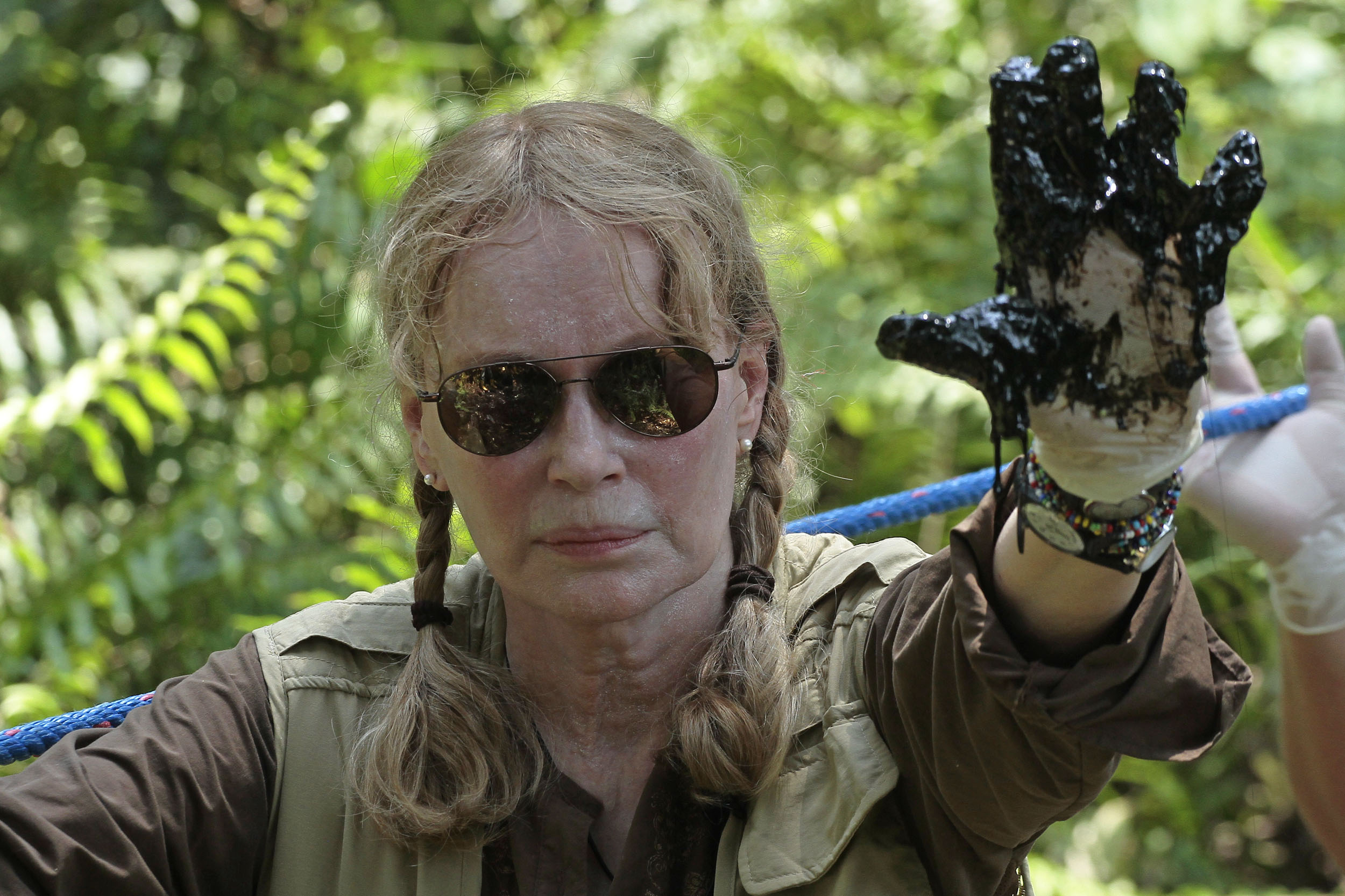 US actress Mia Farrow shows her left hand soiled with oil during a visit to an Amazonic area affected by pollution created by US oil company Chevron, in Lago Agrio, Aguarico, Ecuador, on January 28, 2014. AFP PHOTO/JUAN CEVALLOS